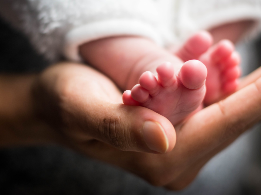 Woman holding newborn baby's small feet